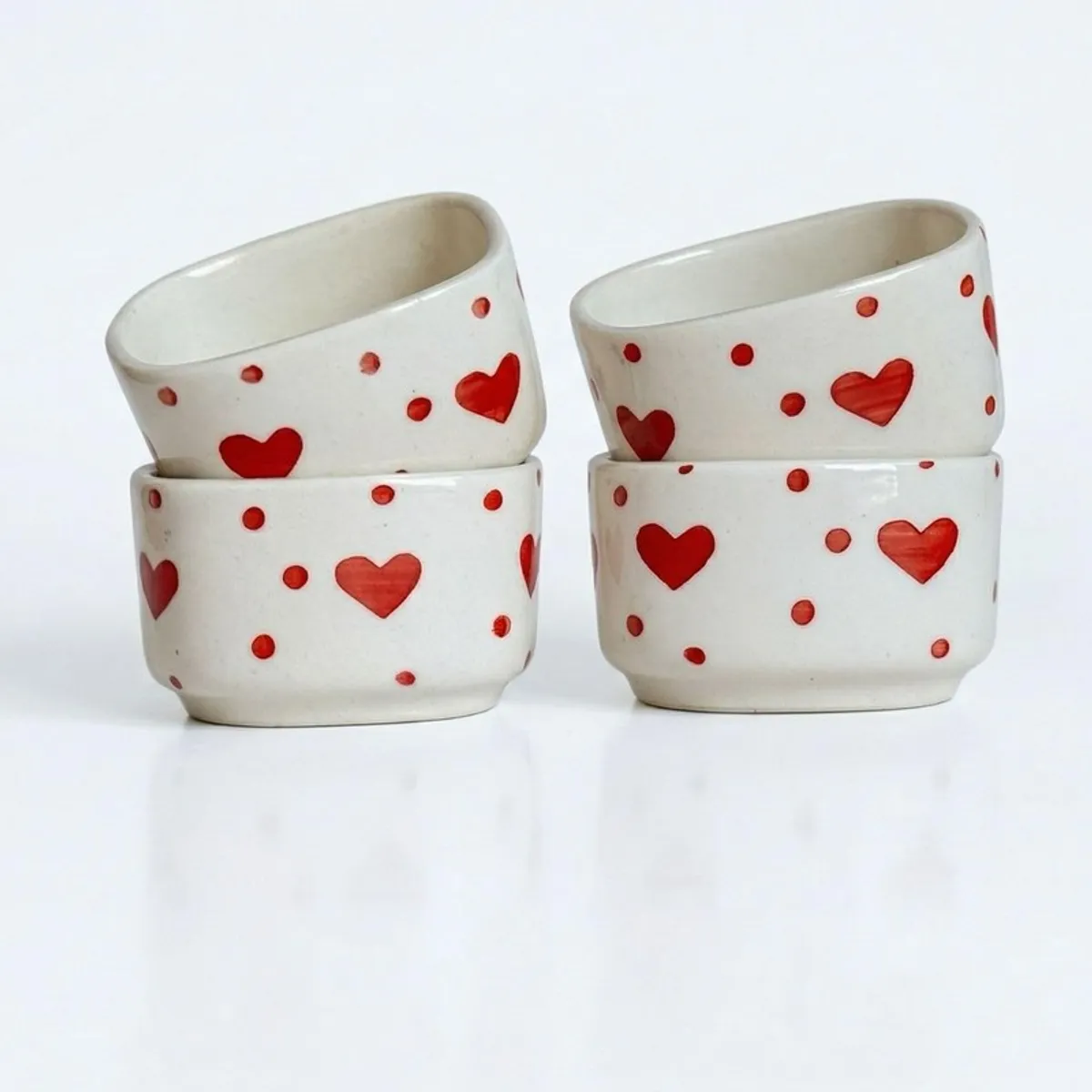 Front view of four white ceramic dip bowls with red hearts and dots