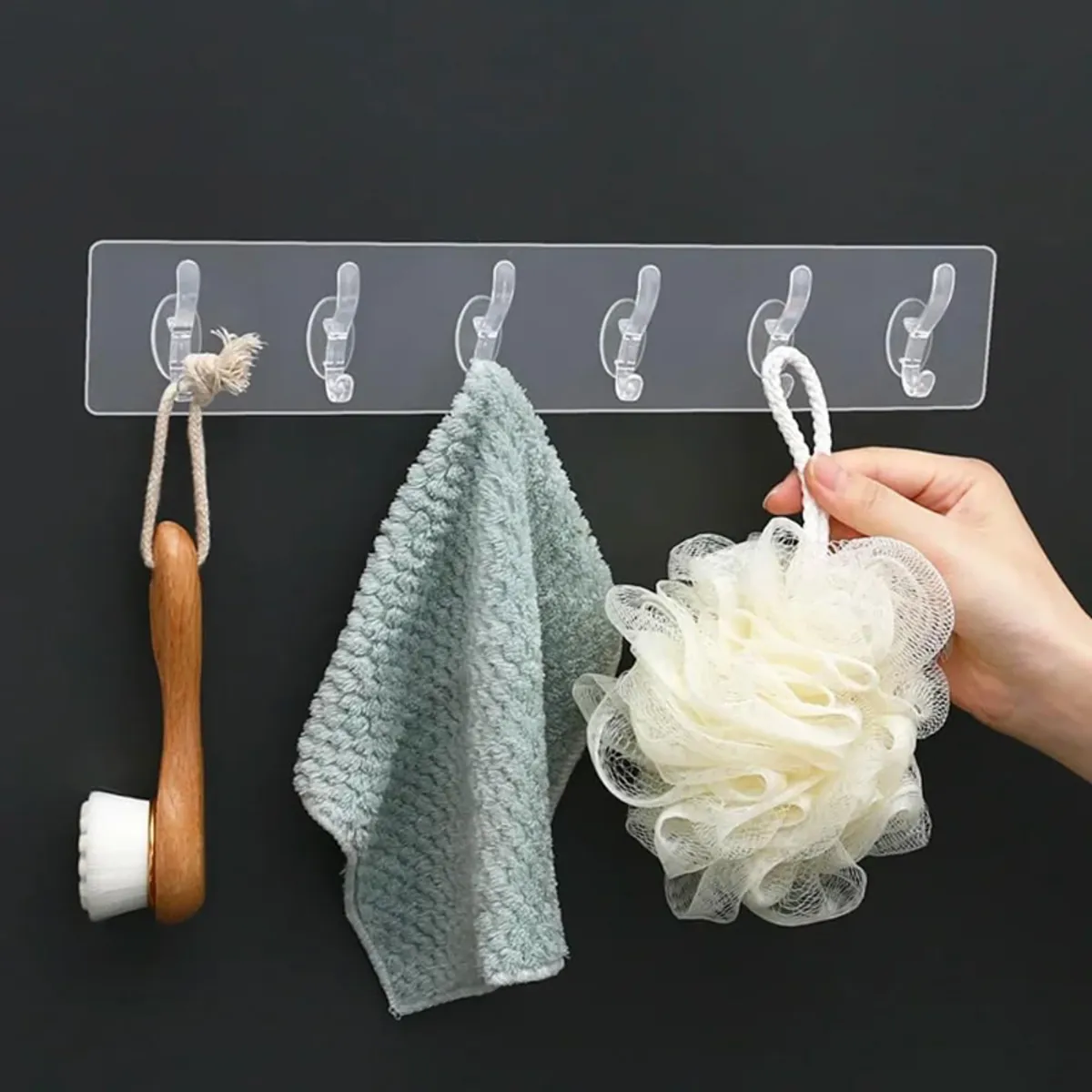 Transparent six-hook strip holding a brush, towel and bath sponge
