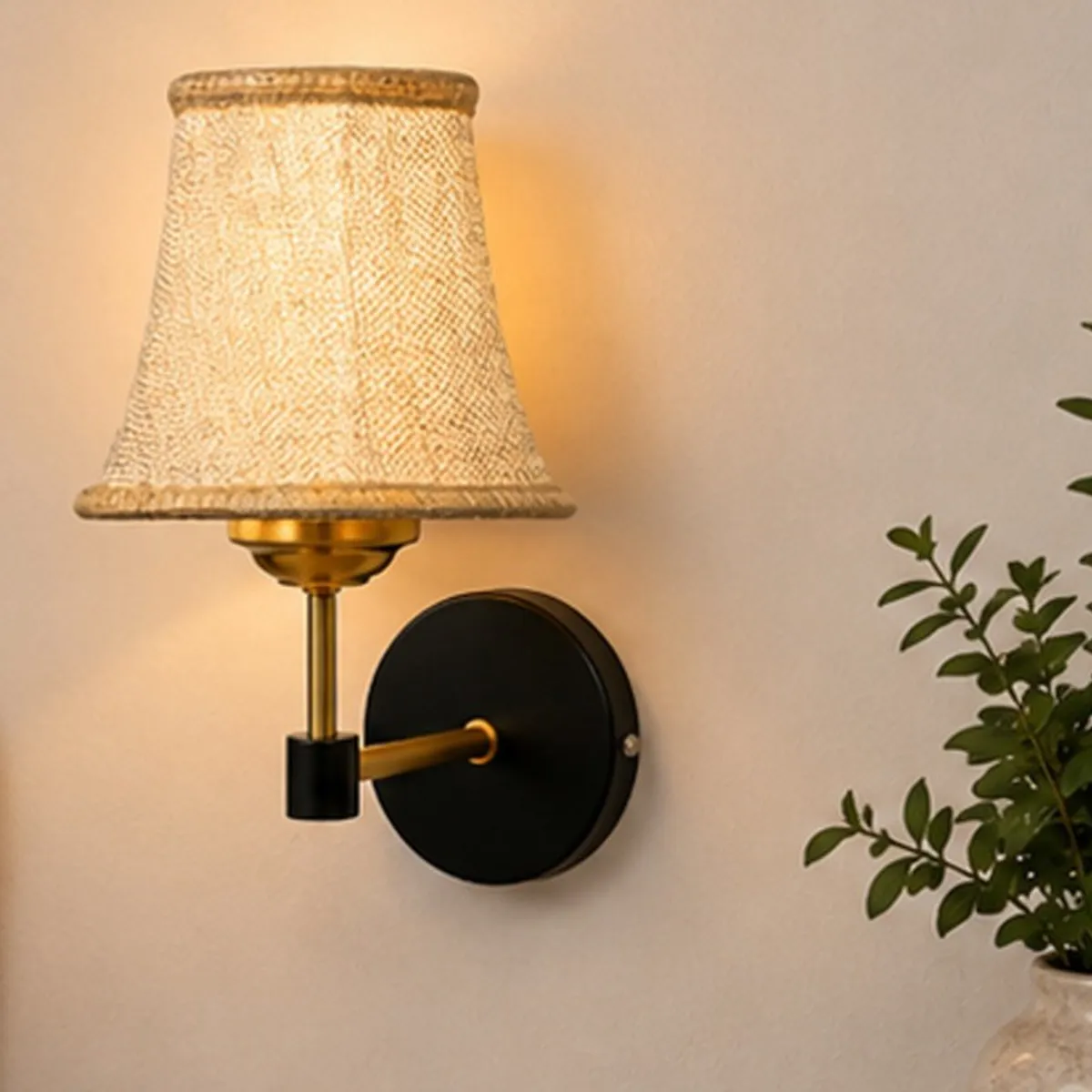 Close-up of beige jute shade and black and gold-toned wall lamp base