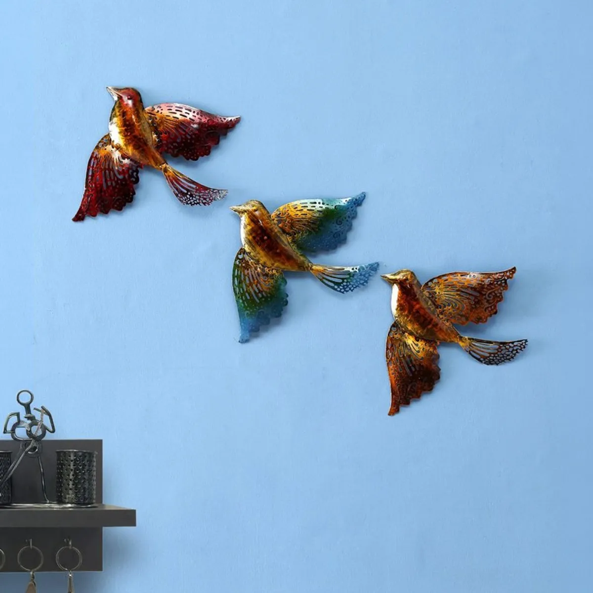 Three bird-shaped metal wall accents displayed on a blue wall