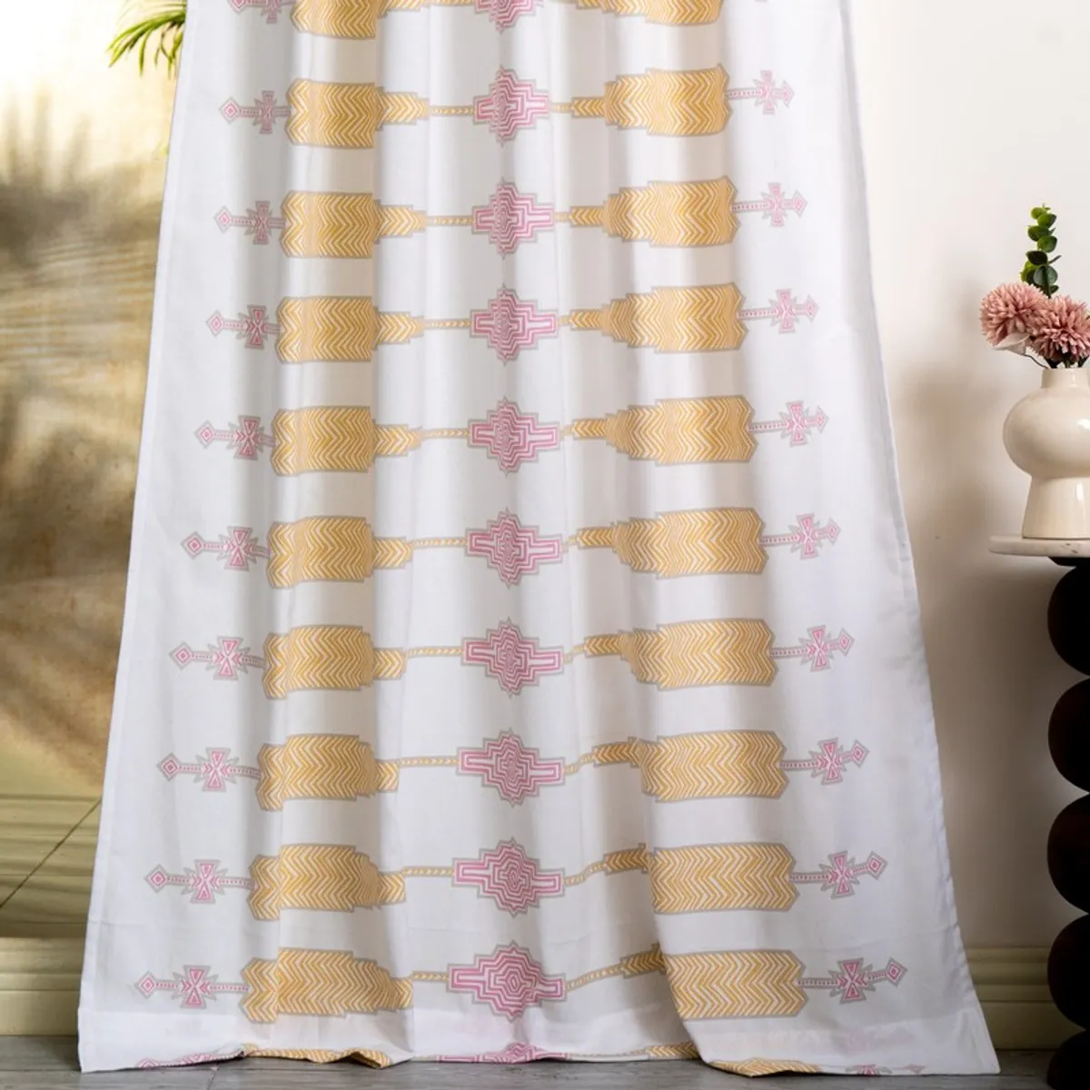 Full-length white curtain with repeating pink and yellow geometric print