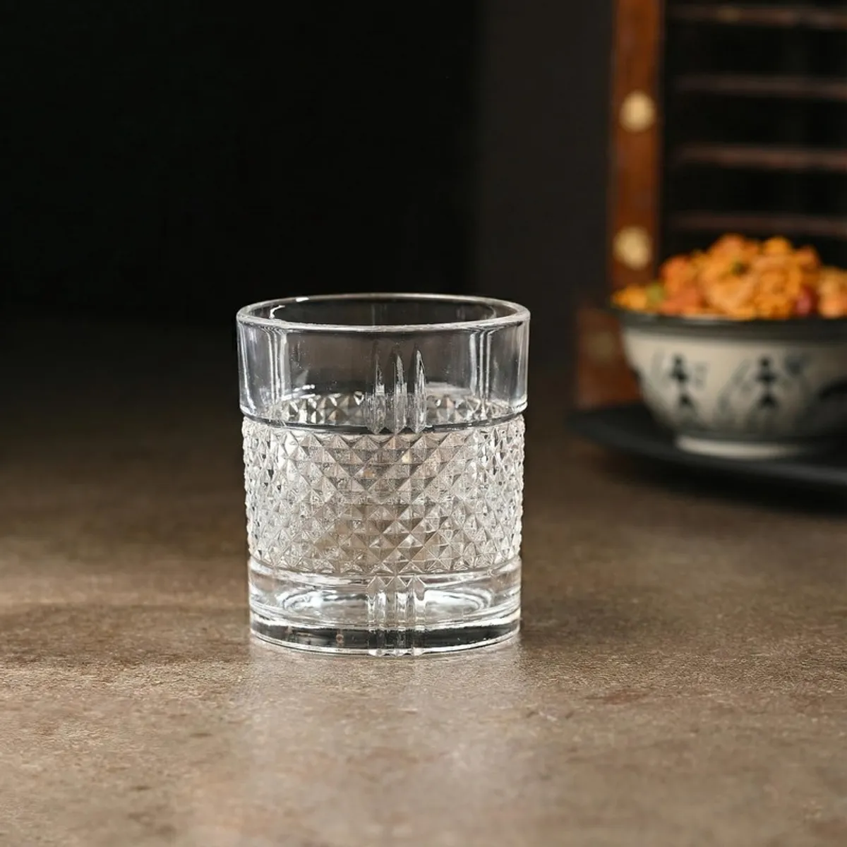 Empty transparent whiskey glass with textured geometric surface