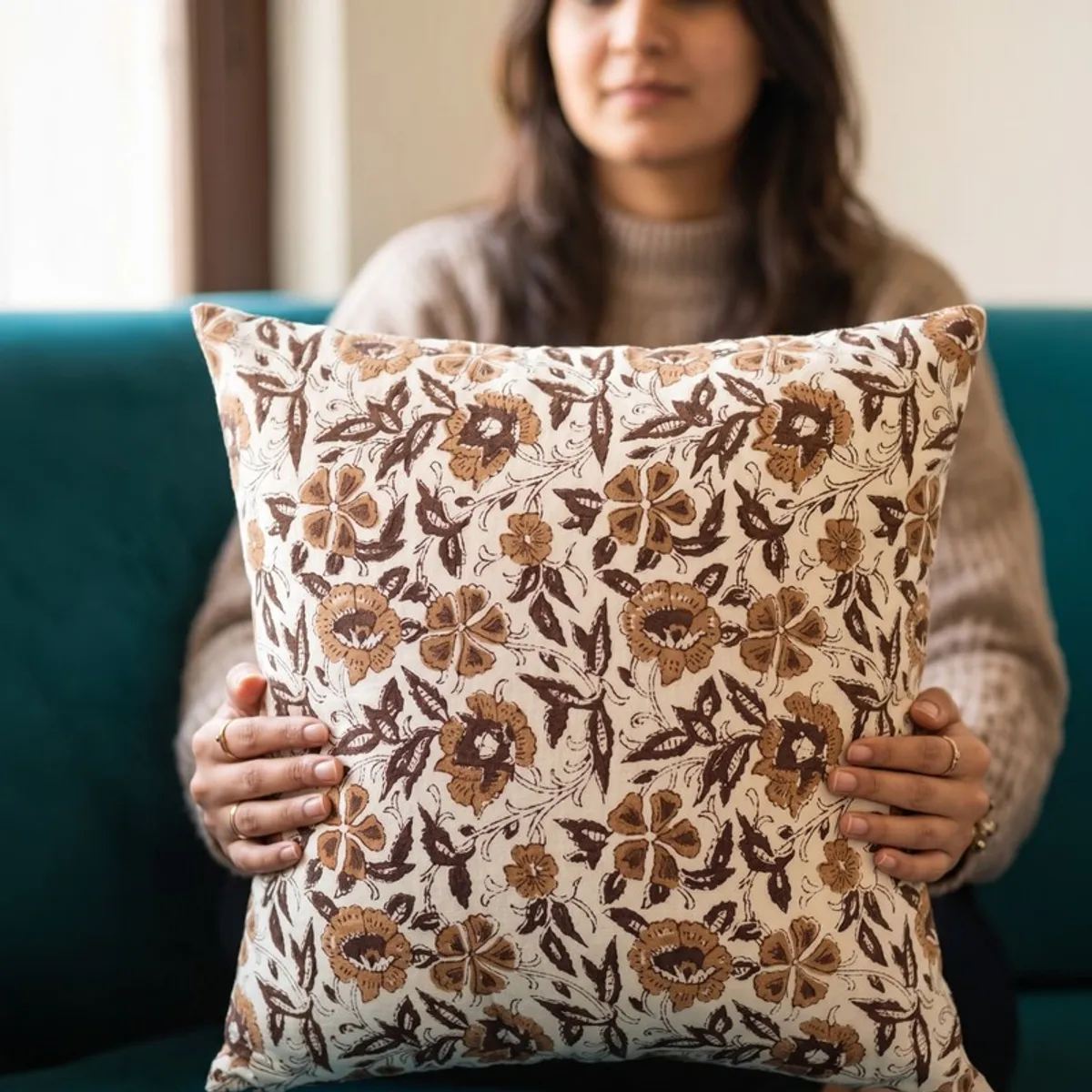 Person holding a white cushion cover with brown floral print