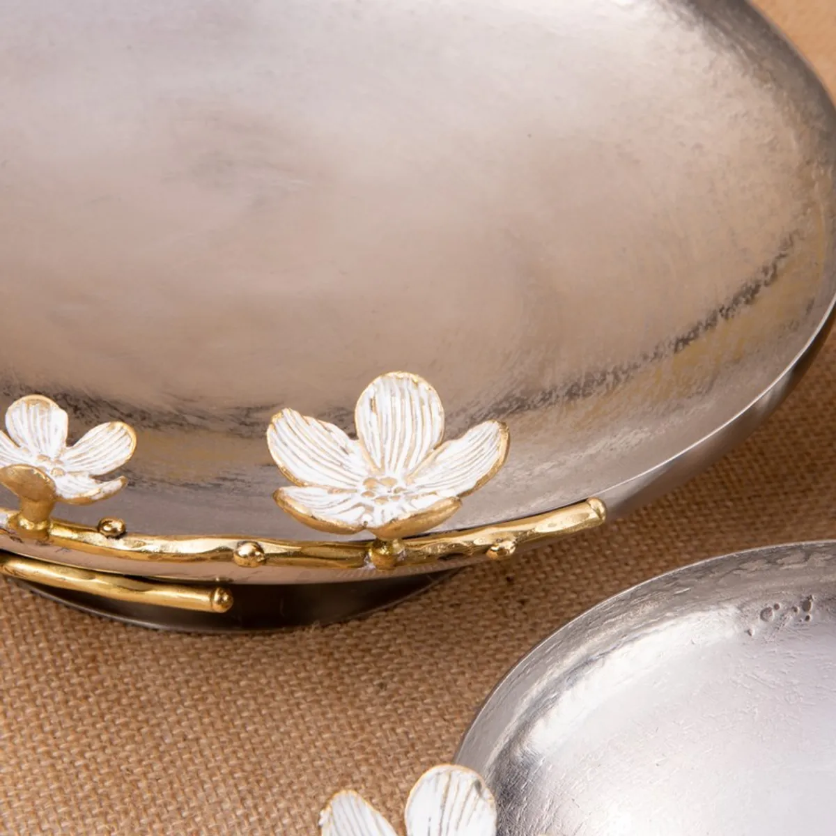 Close-up of glossy silver bowl surface with white and gold floral rim