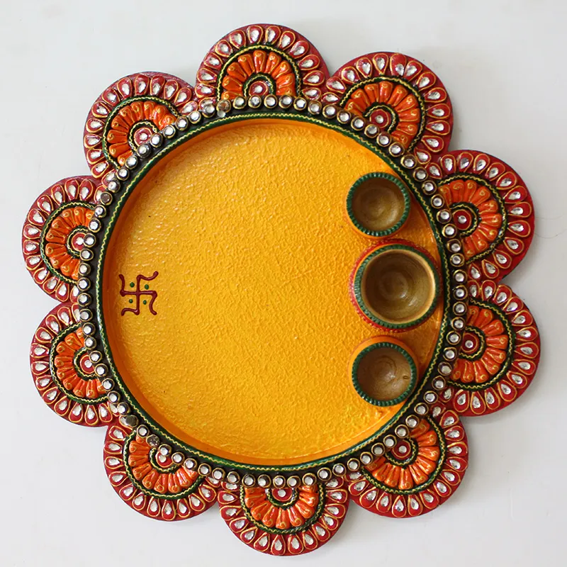 Top view of handcrafted yellow and orange pooja thali with three bowls
