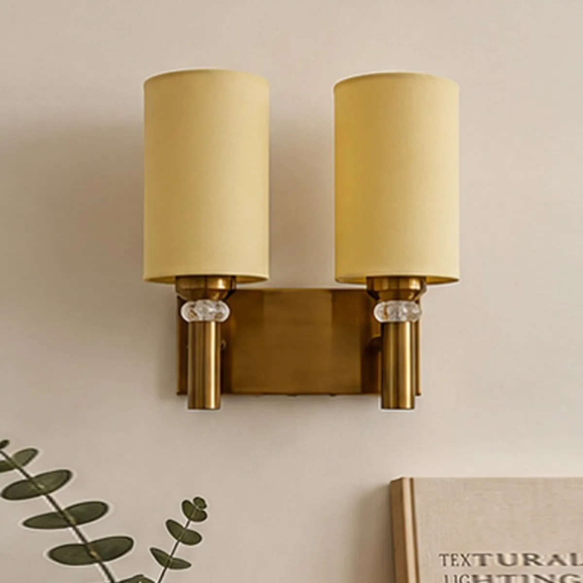 Close-up of twin ivory cotton shades and gold-toned wall lamp base