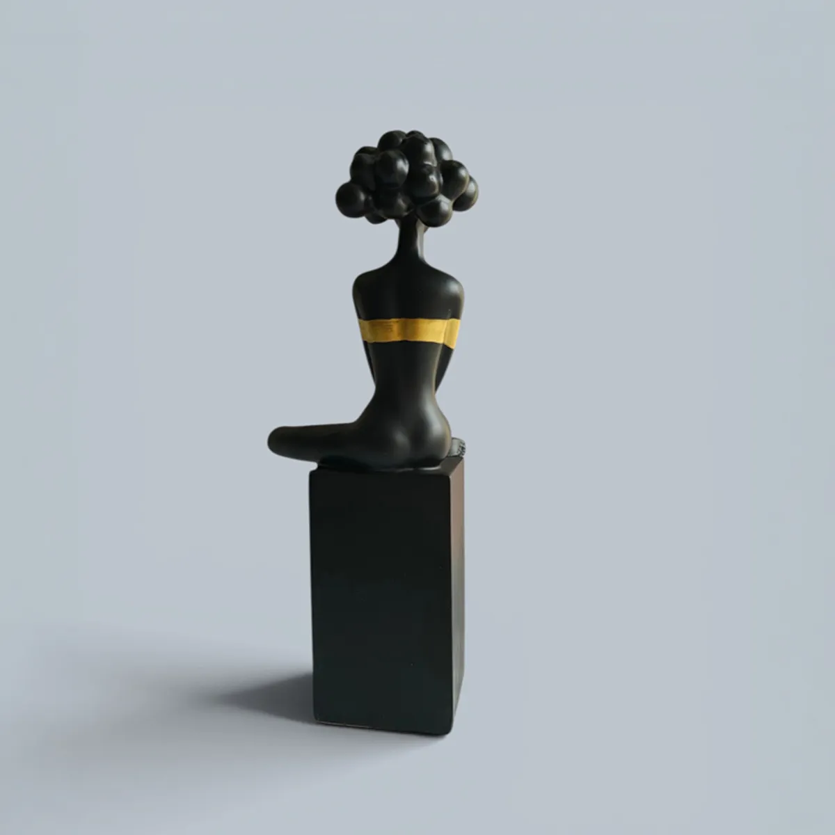 Rear view of the black and gold sitting lady showpiece on its rectangular base