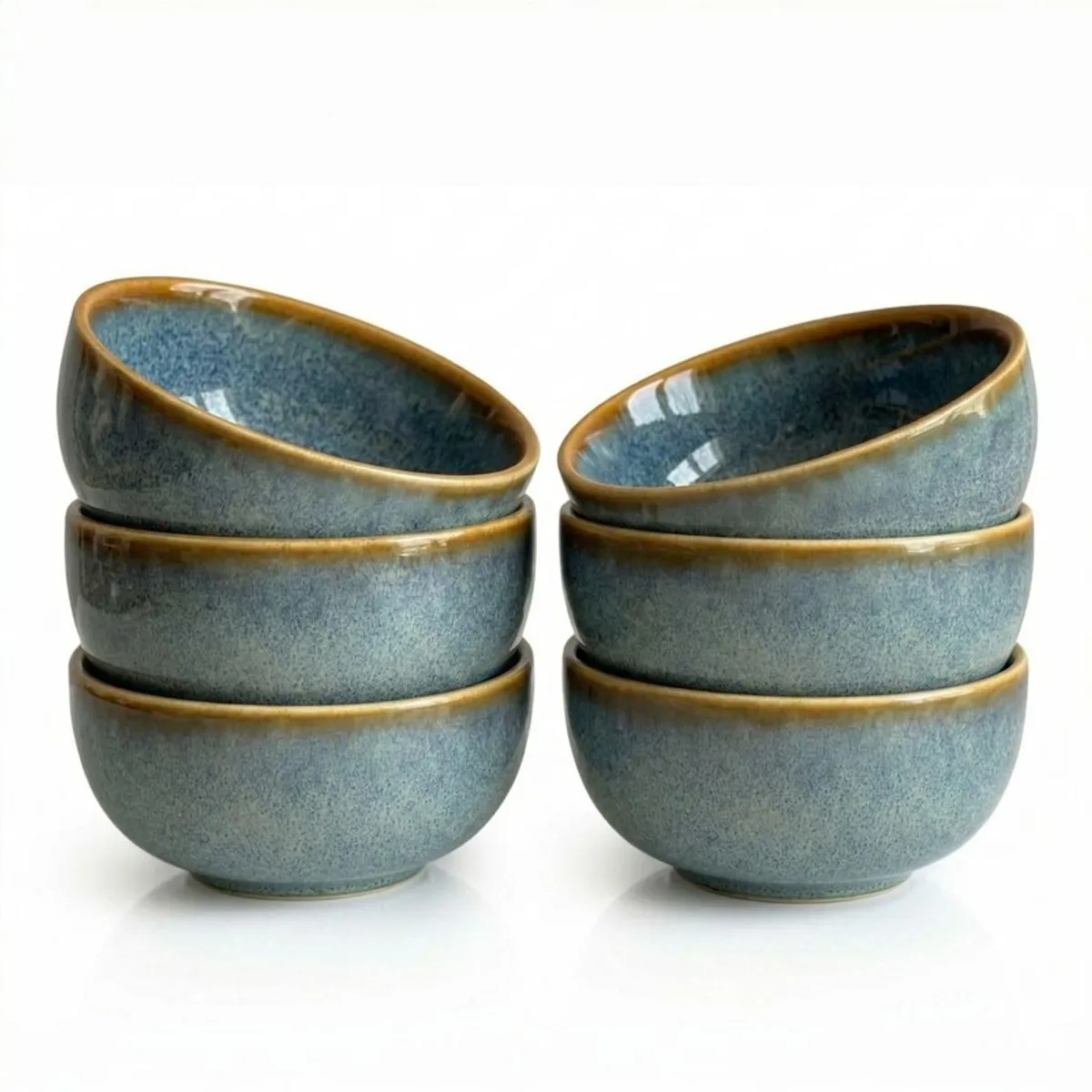 Six glossy blue-grey ceramic bowls stacked against a white background