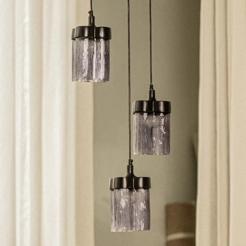 Close view of three cylindrical smoky glass pendant lamps with black tops