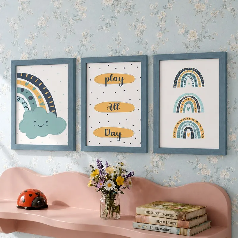 Three blue-framed rainbow art prints displayed on a floral wallpapered wall