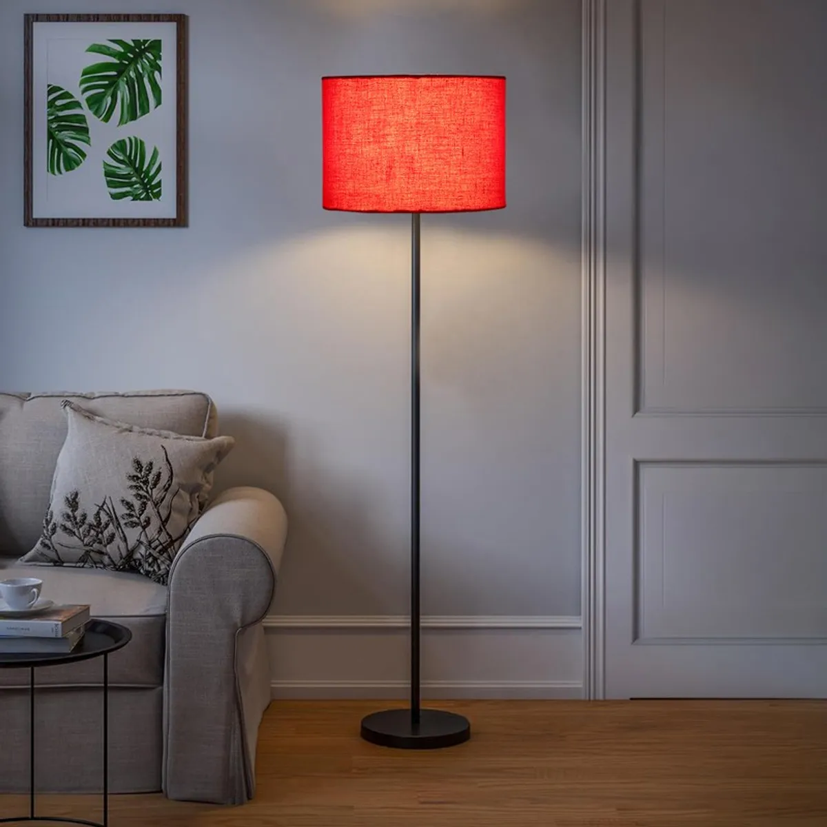 Lit red drum shade floor lamp in a living room setting
