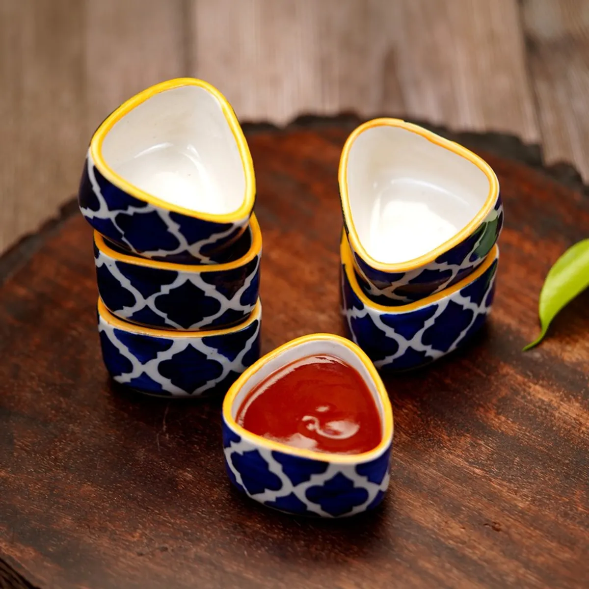 Six blue and white patterned dip bowls with one filled with sauce
