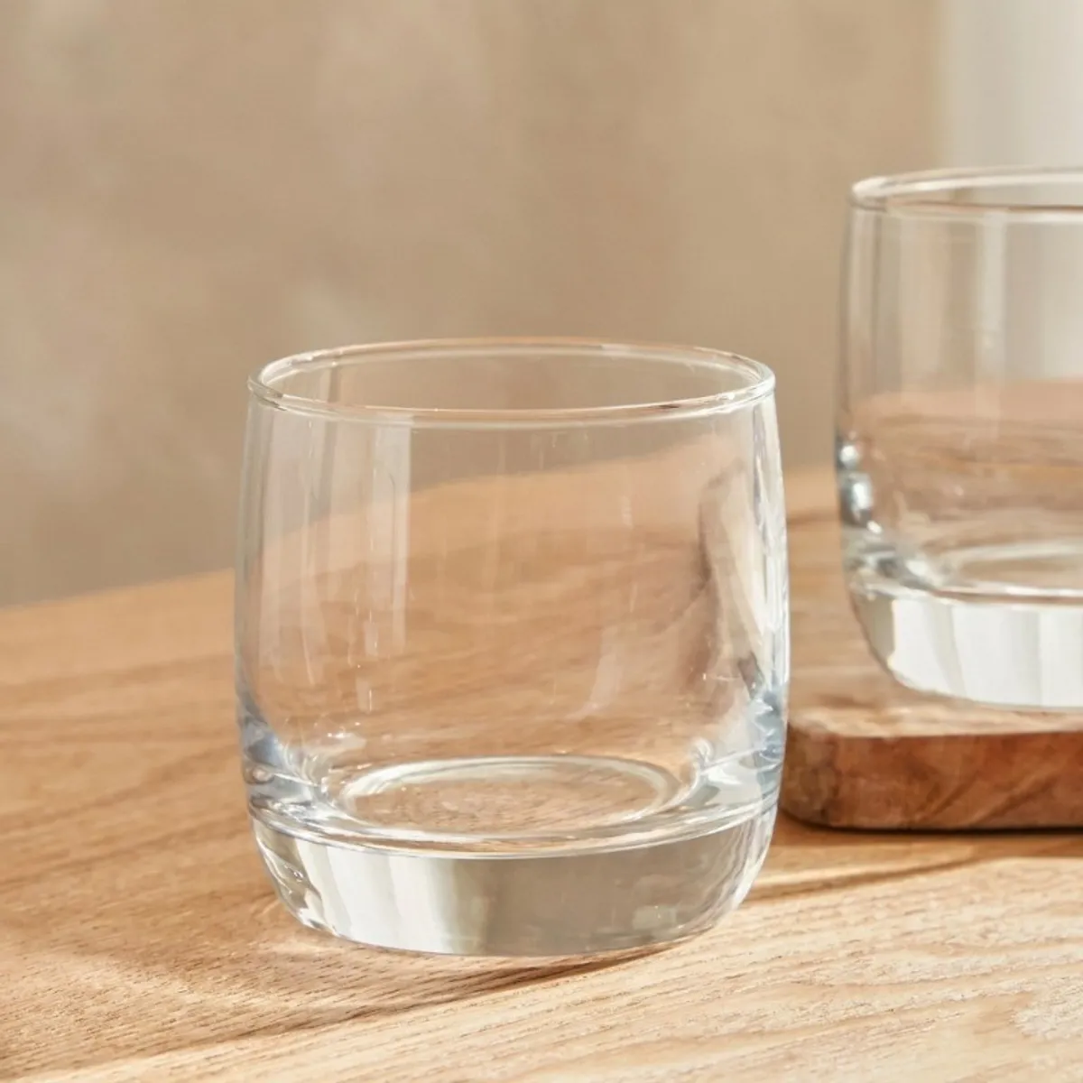 Single transparent cylindrical drinking glass shown on a wooden tabletop