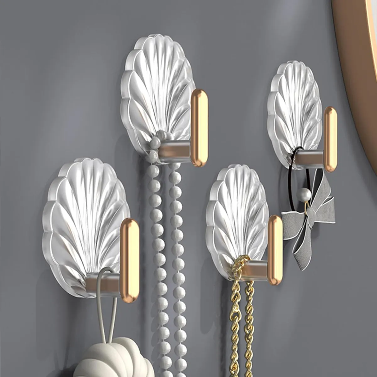 Four shell-shaped wall hooks displayed with jewellery and accessories on a dark wall