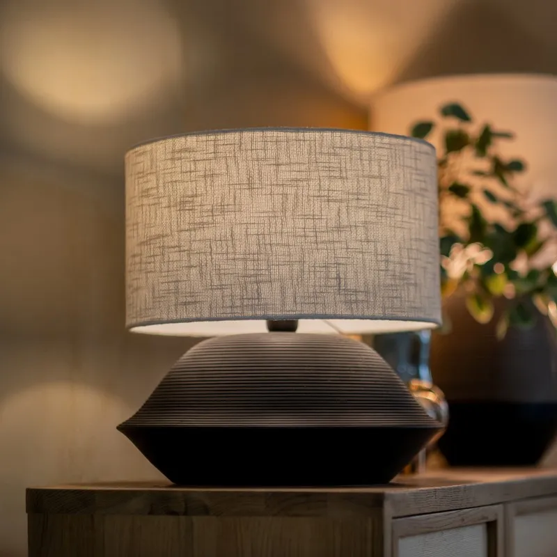 Side view of black ribbed table lamp with textured beige shade