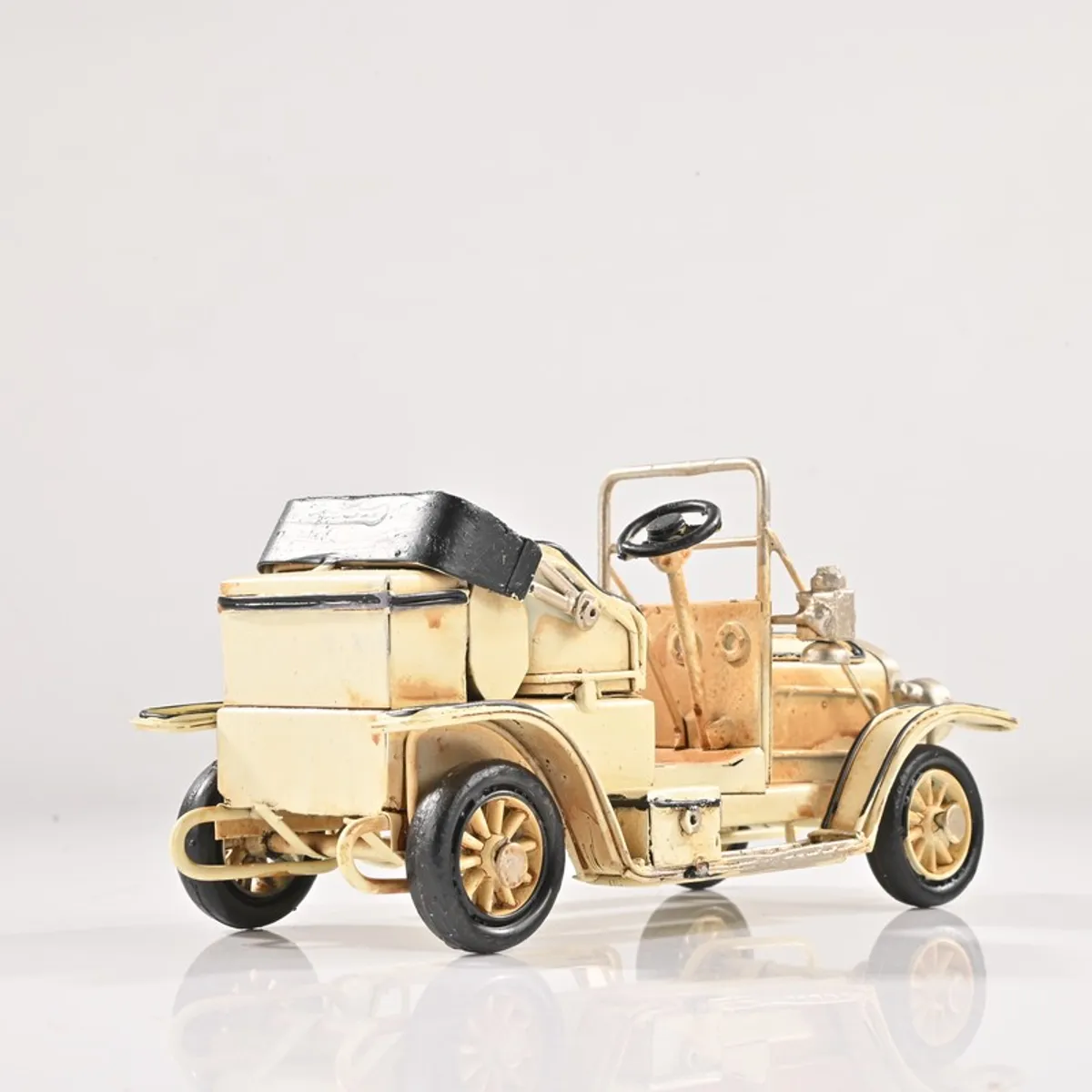 Rear angled view of an ivory vintage car showpiece on a white background