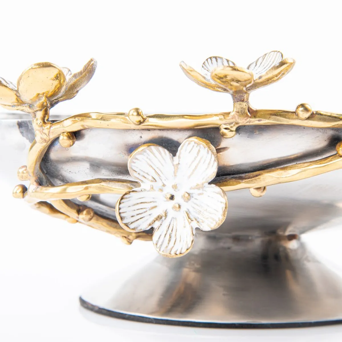 Close-up of gold branches and white floral detailing around a silver bowl