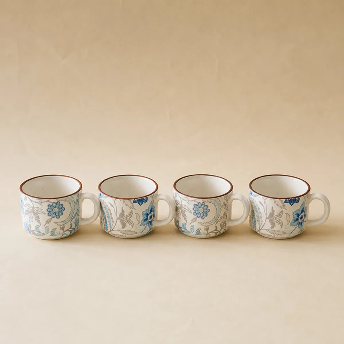 Four matching floral ceramic tea cups arranged in a row