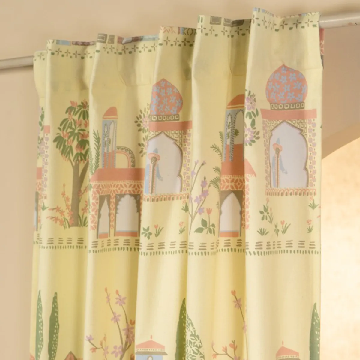 Yellow curtain displaying repeating palace, tree and floral pattern