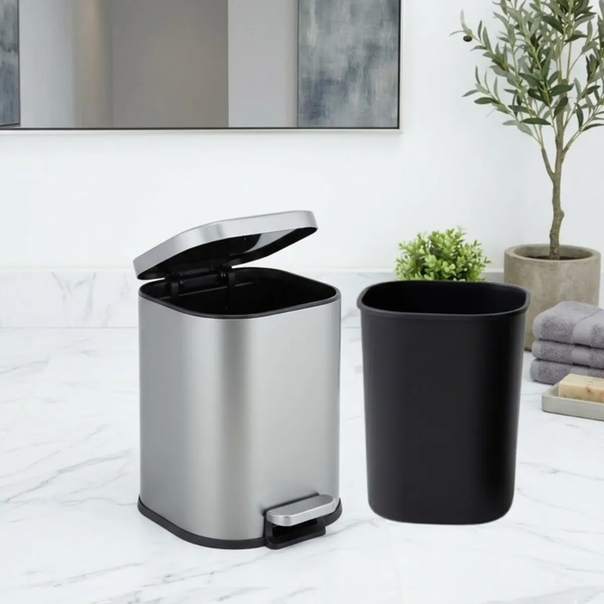Grey metal pedal dustbin with removable black inner bucket placed beside it