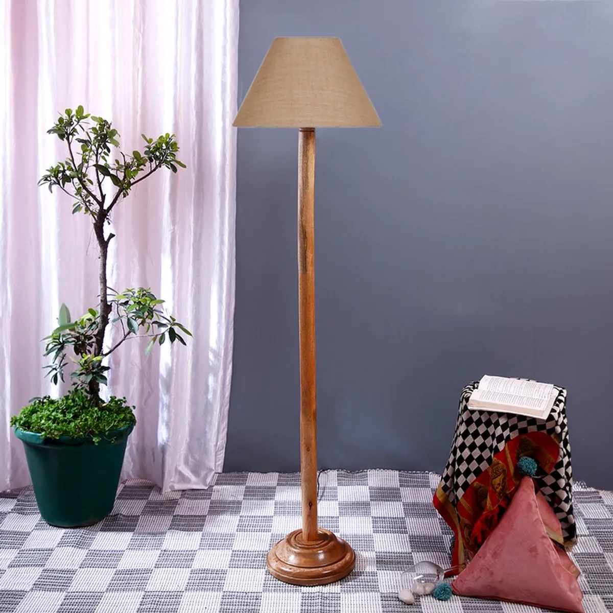 Wooden floor lamp with unlit conical shade beside a potted plant