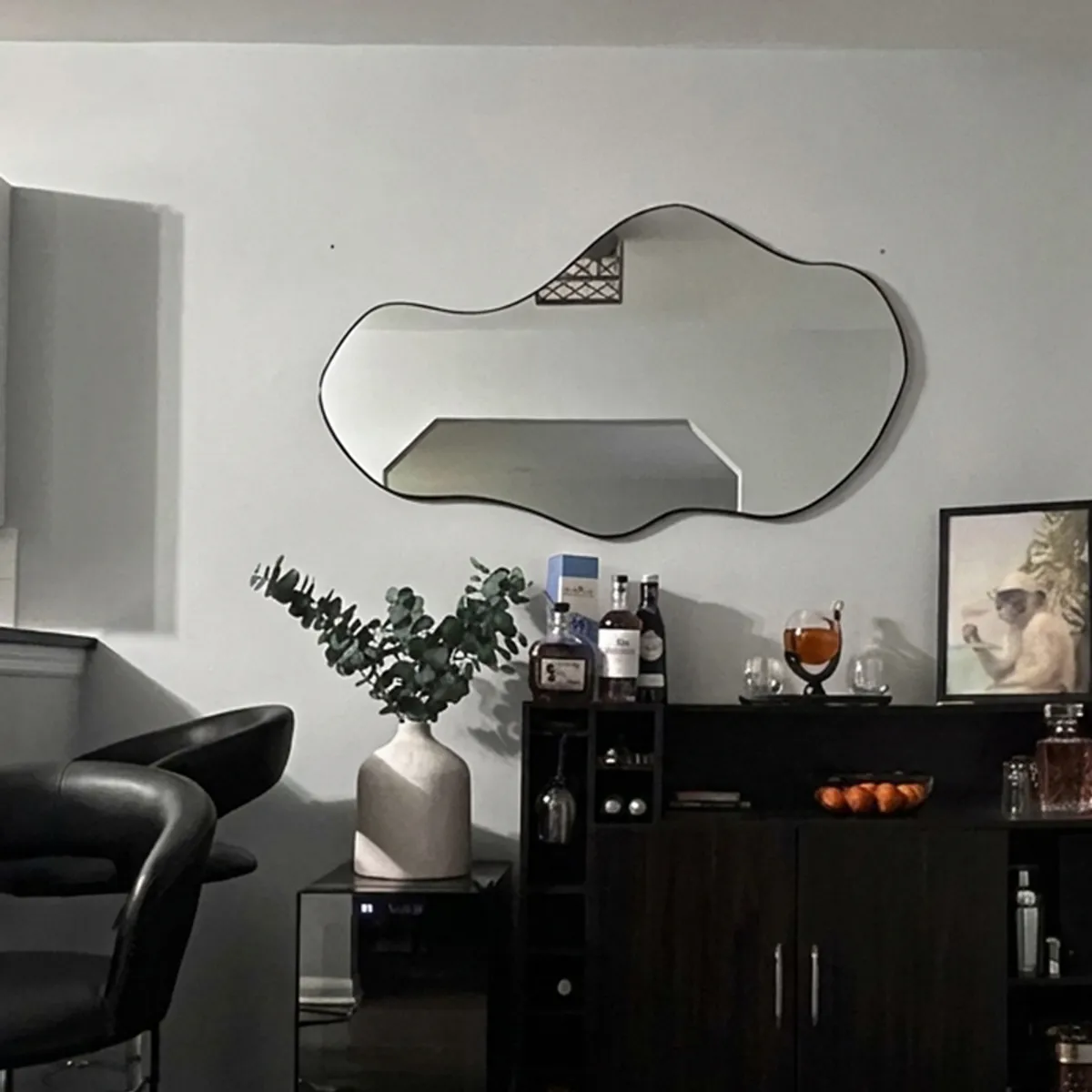 Free-form wall mirror above a dark sideboard in a contemporary room
