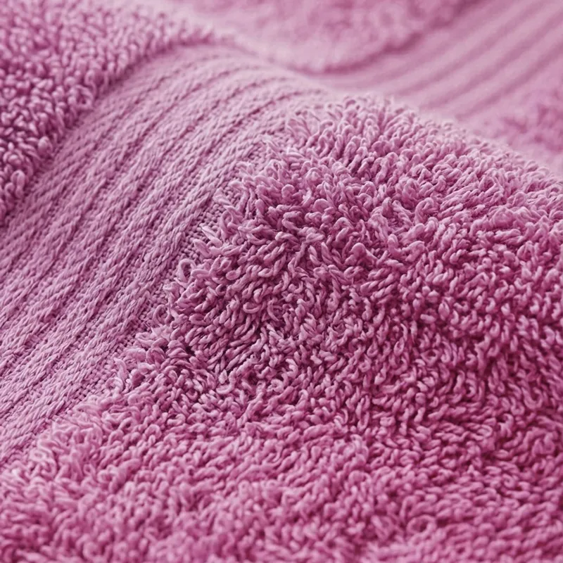 Close-up of pink towel fabric with textured cotton loops and border bands