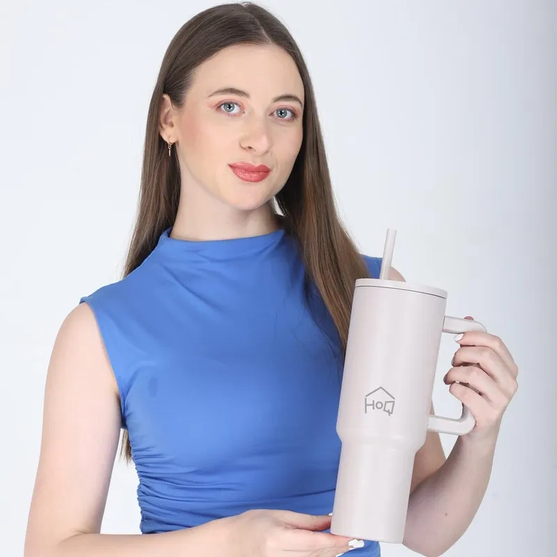 Woman holding an oat beige tumbler with handle and straw