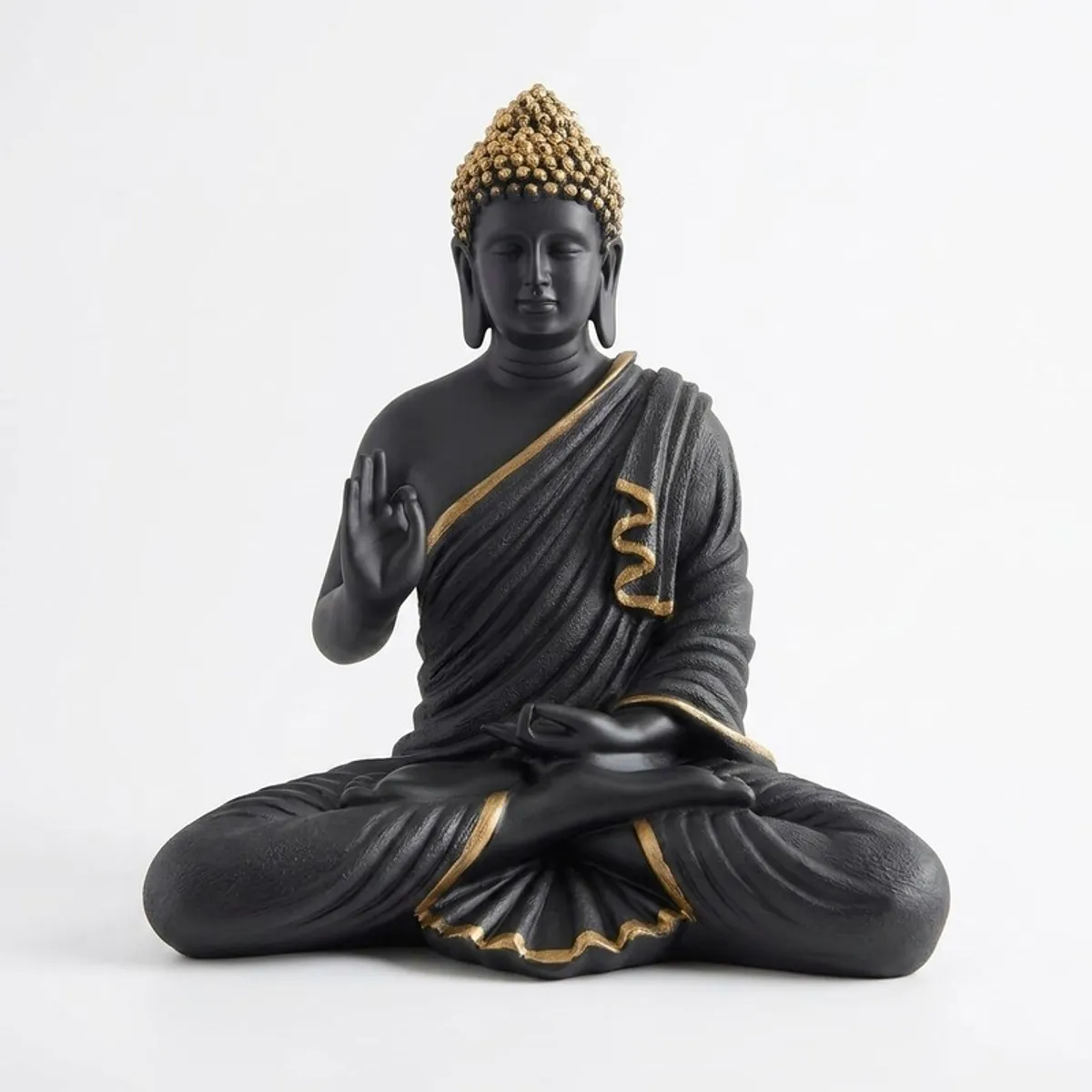Front view of a black and gold meditating Buddha idol on a white background