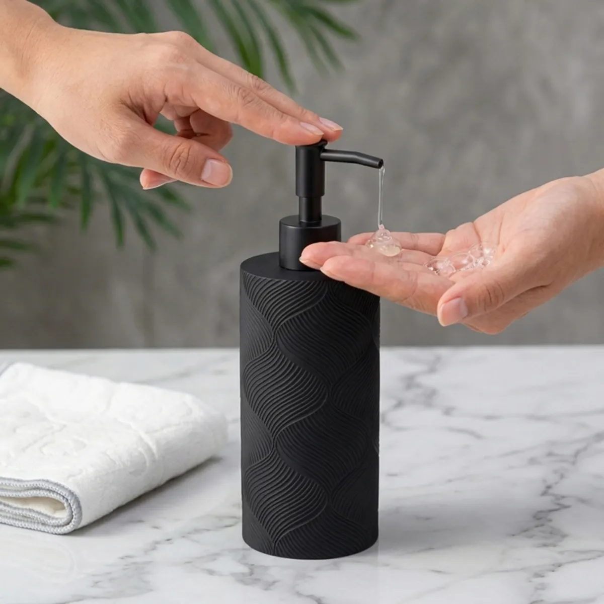 Hand pressing black soap dispenser pump over an open palm