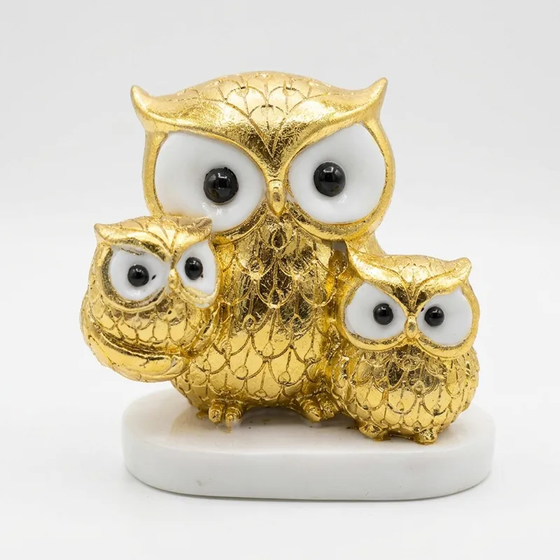 Close-up of a gold and white owl family showpiece on a white base