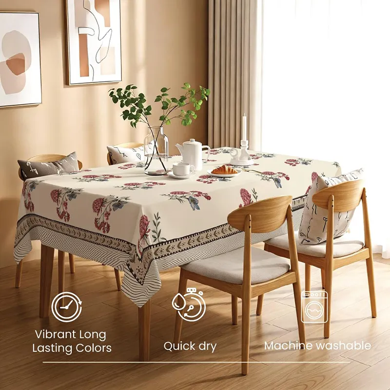 Rectangular white table cover with floral motifs draped over a wooden dining table