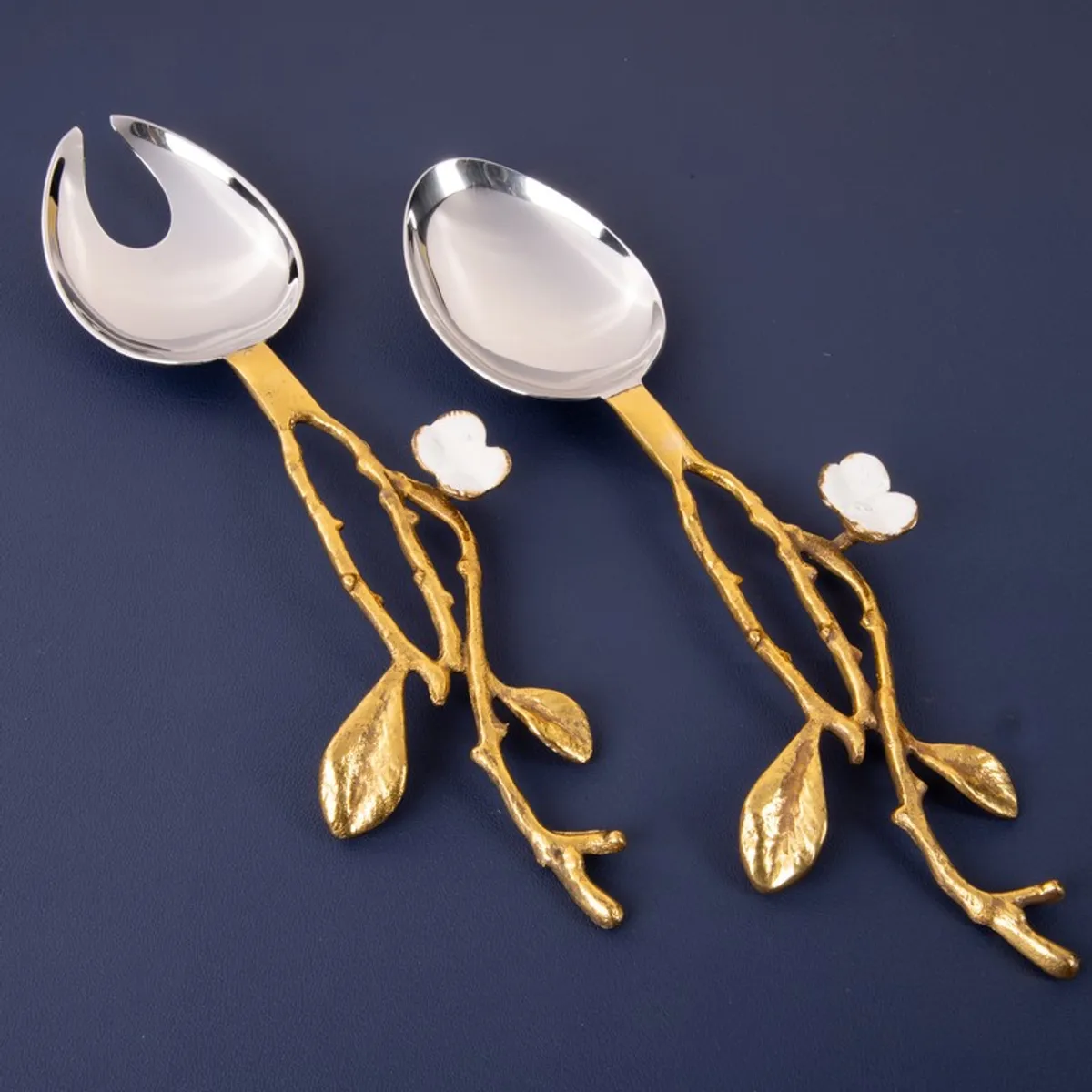 Silver and gold floral branch salad spoon and fork on a dark background