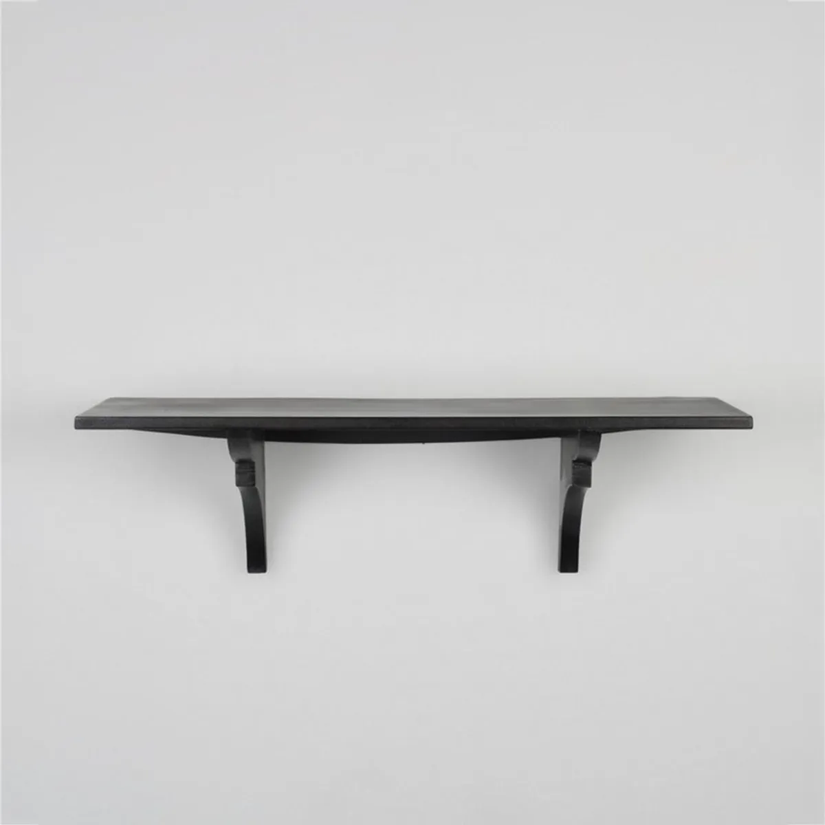 Front view of a black wooden wall-mounted shelf against a white wall