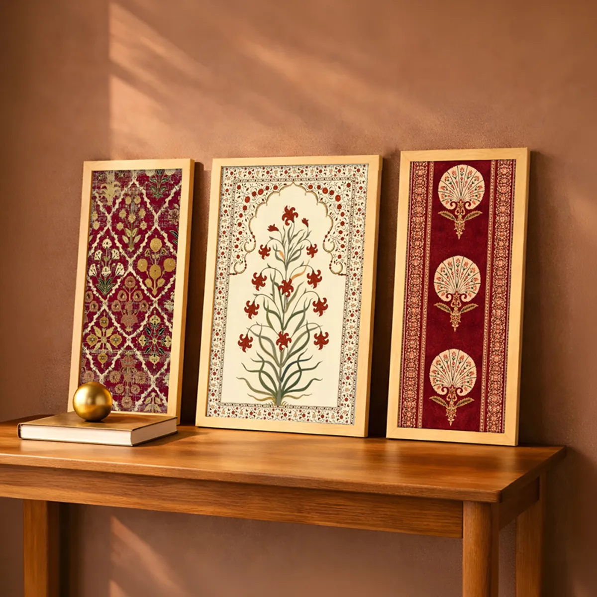Set of three framed floral and patterned wall art pieces leaning on a wooden console