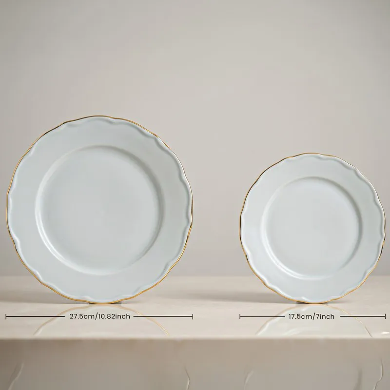 Large and small white plates with scalloped edges and gold rims