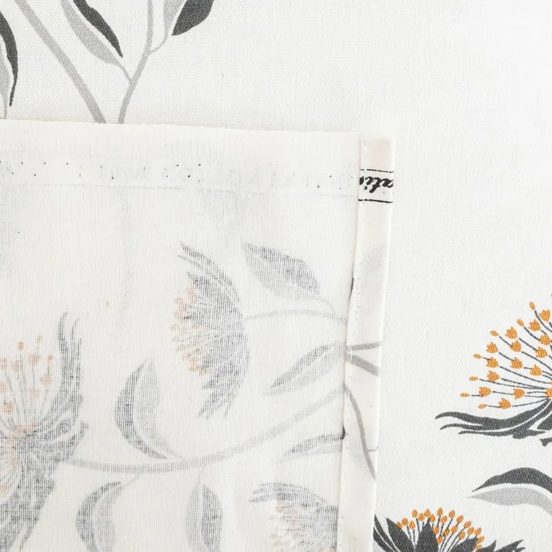 Close-up of folded edge and floral print on white bedsheet