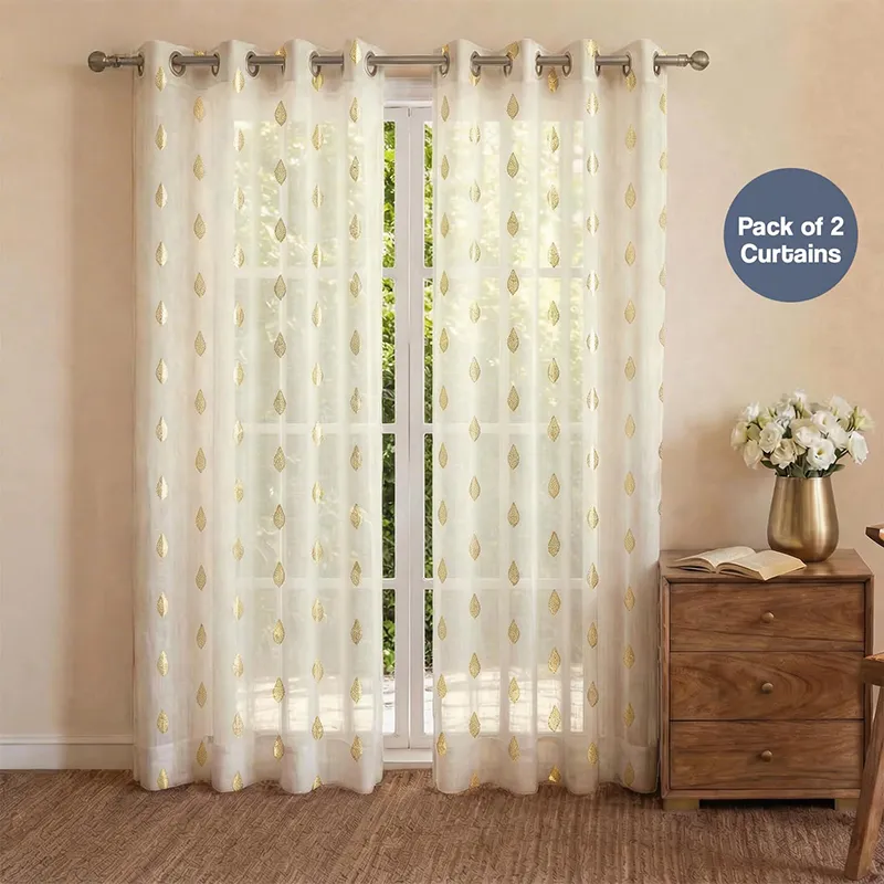 Set of white and gold patterned curtains hanging on a window with eyelet top