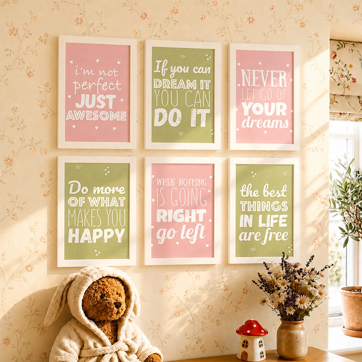 Six framed typography wall art pieces in pink and green on a cream floral wall.
