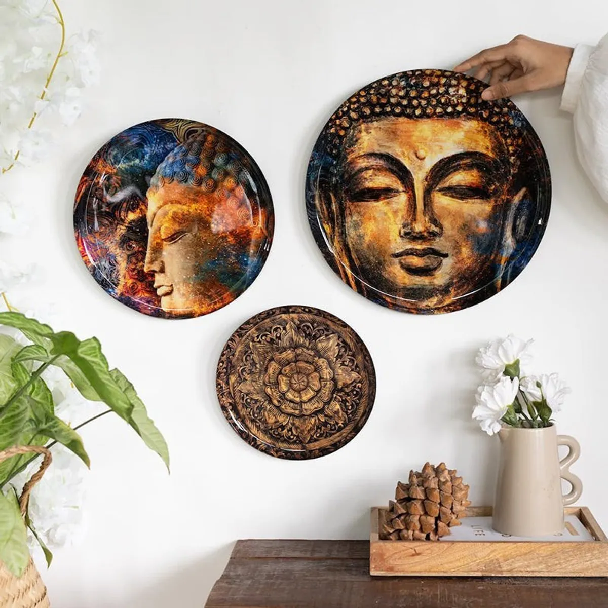 Three Buddha wall plates shown together on a white wall.