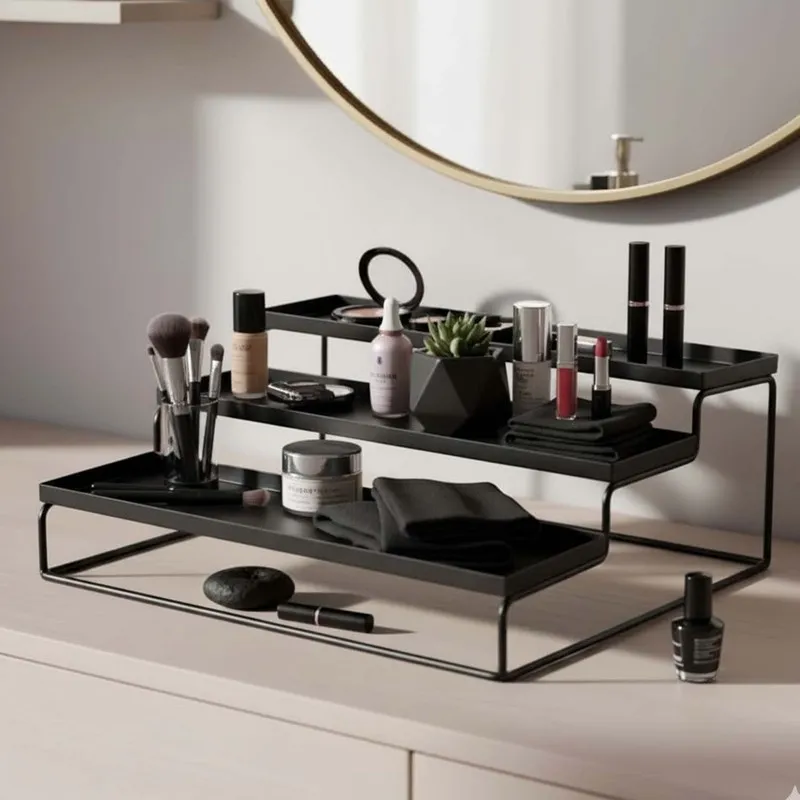 Black tiered metal organiser on a dressing table holding makeup and folded cloths.