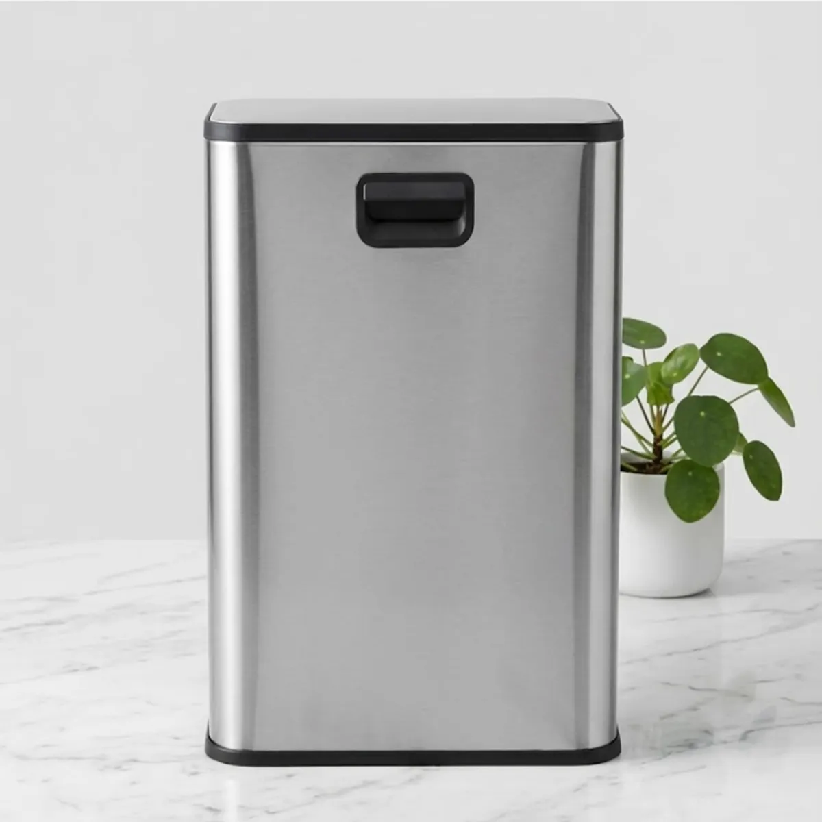 Rear view of a silver rectangular dustbin with black trim and handle