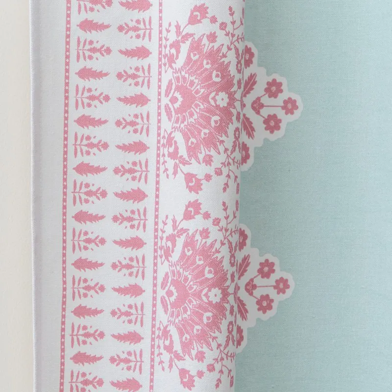 Close-up of pink floral and leafy border detailing on aqua curtain fabric