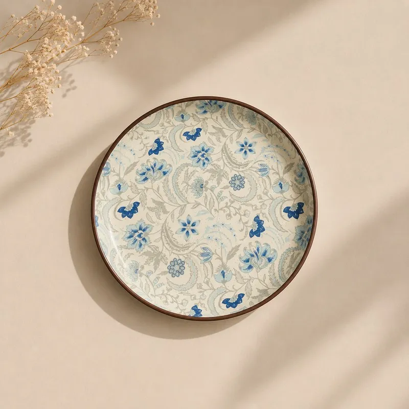 Top view of a round dinner plate with blue floral motif and brown rim
