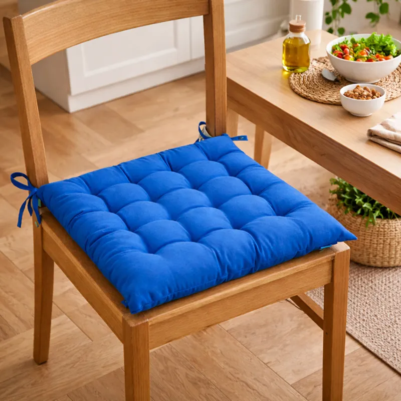 Blue square tufted chair pad secured to a wooden dining chair.