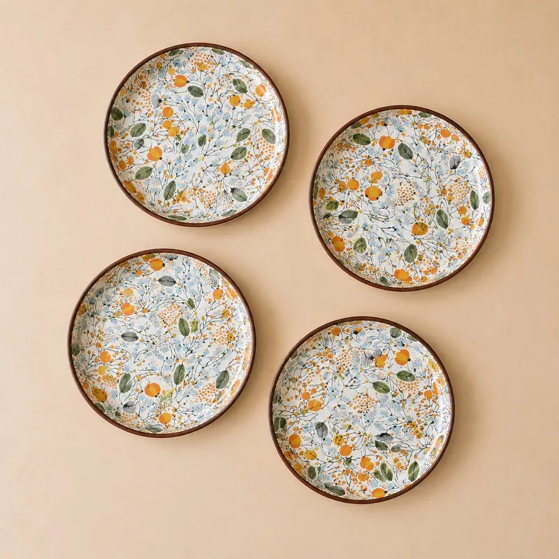 Four botanical-pattern ceramic plates shown from above