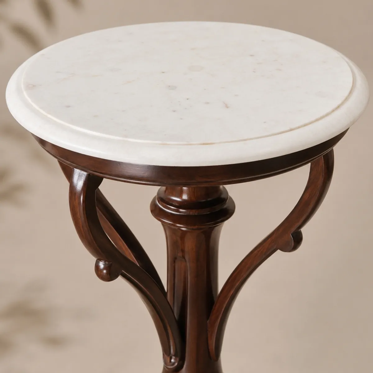 Close-up of the round white tabletop and brown carved wooden frame