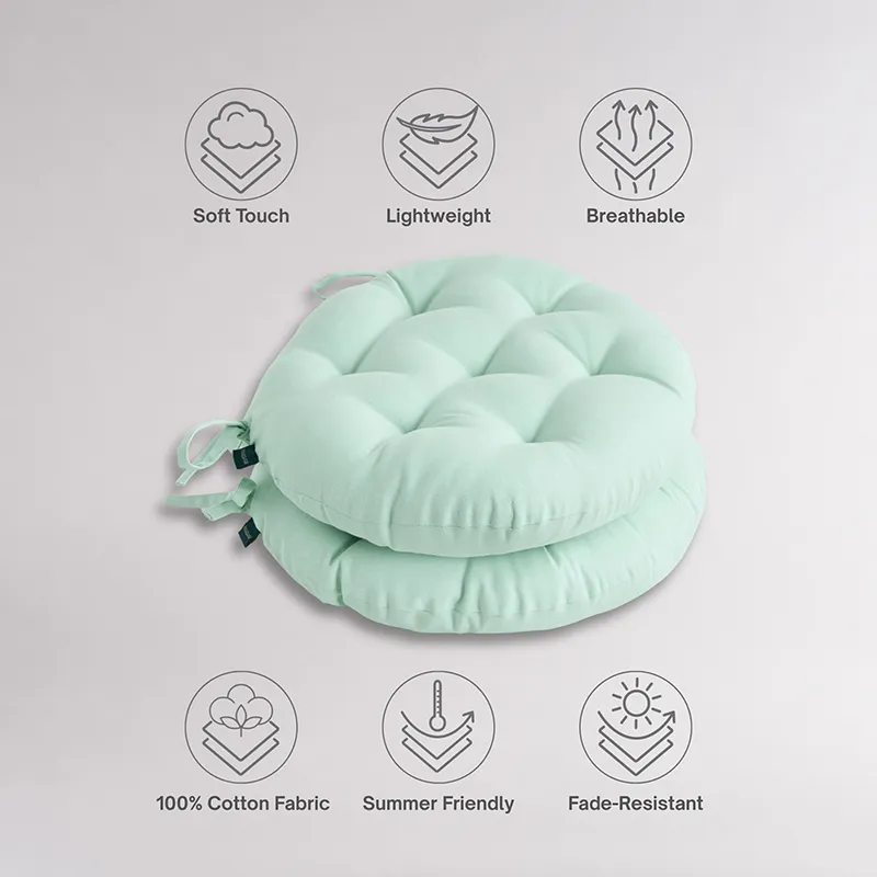 Stacked sage green round chair pads with tufted surface and tie-up strings