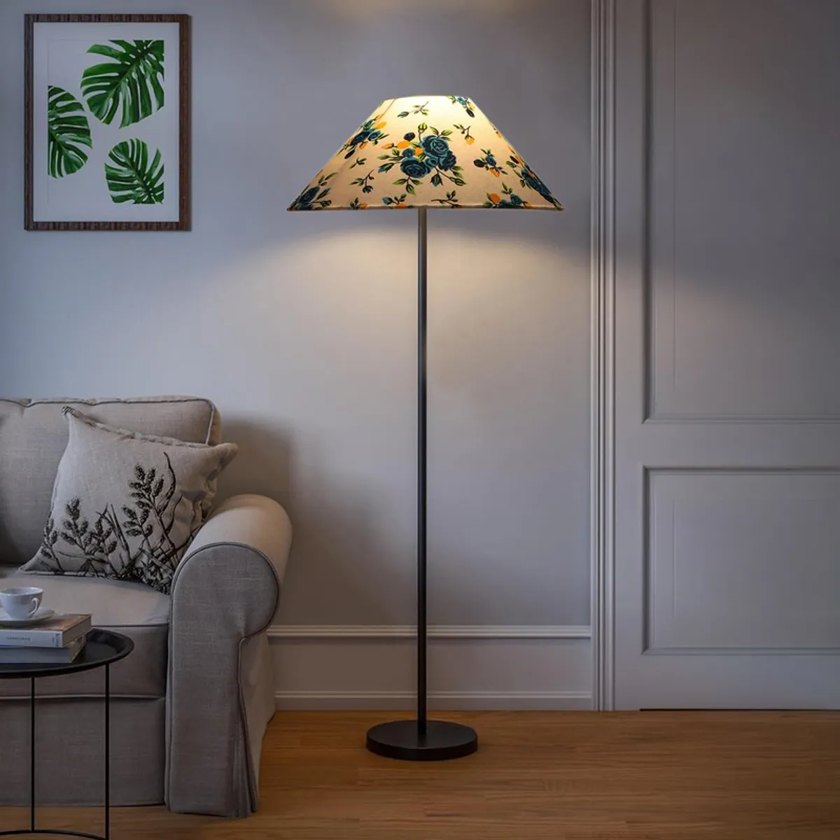Blue floral floor lamp glowing beside a sofa in a softly lit room