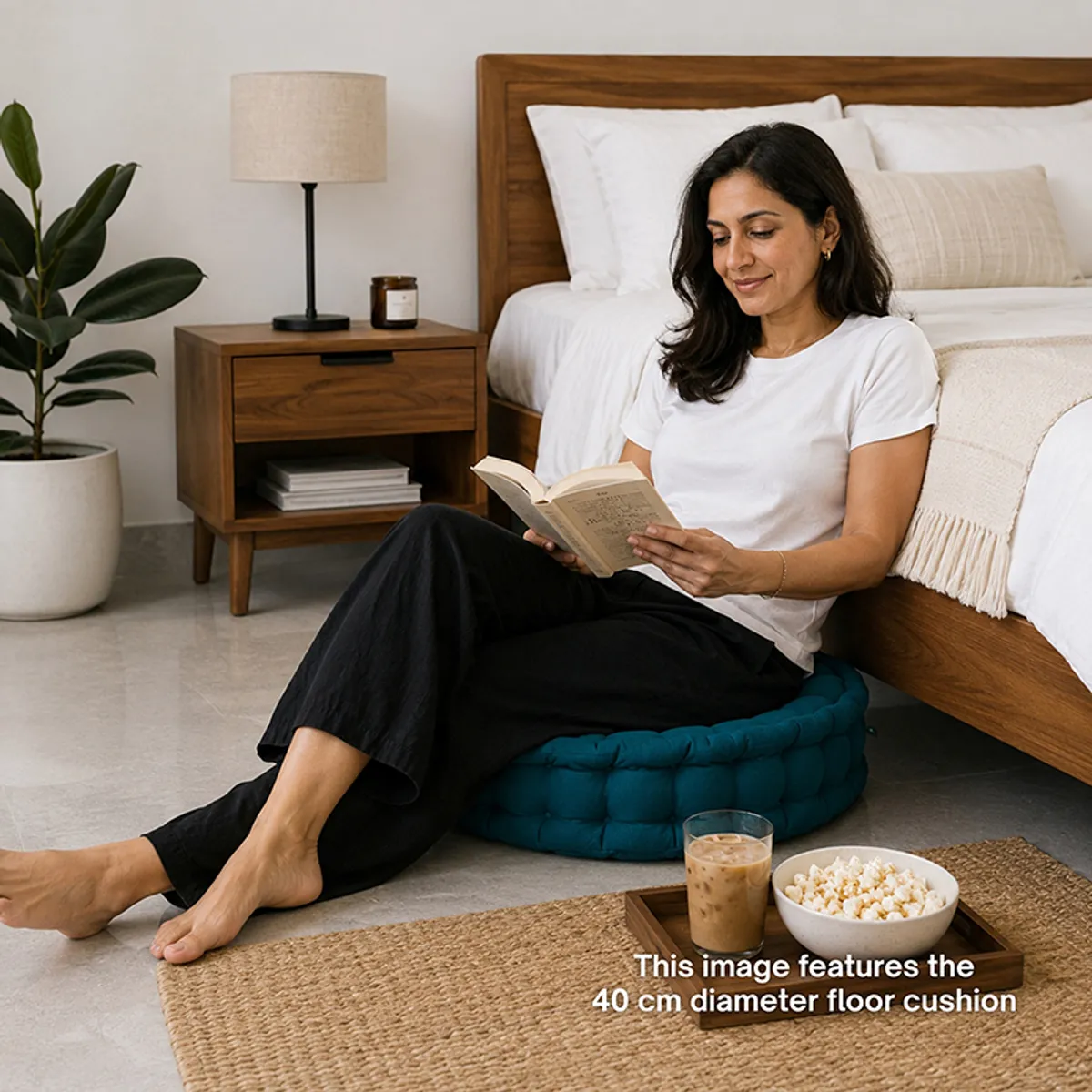 Botanical green round floor cushion shown in a bedroom reading setting.